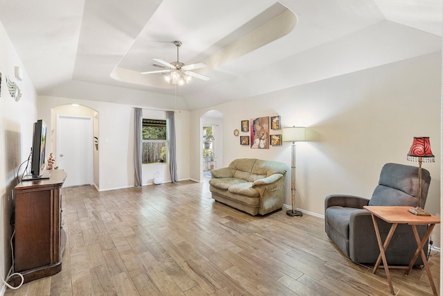 414 Laurel Sage Dr, Houston, TX 77339 - living room with arched walkways, a tray ceiling, ceiling fan, light wood finished floors, and baseboards