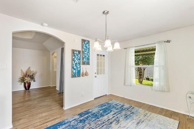 414 Laurel Sage Dr, Houston, TX 77339 - unfurnished dining area featuring arched walkways, light wood-type flooring, a chandelier, and baseboards