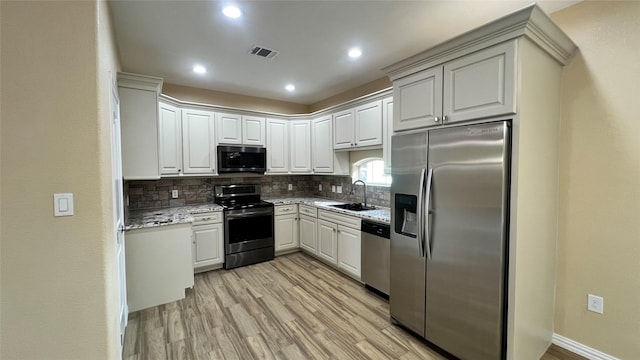 712 Lettie St, Richmond, TX 77469 - kitchen featuring appliances with stainless steel finishes, a sink, light wood-style flooring, decorative backsplash, and light stone counters