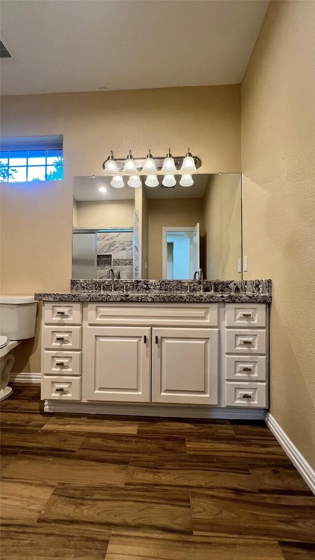 712 Lettie St, Richmond, TX 77469 - full bathroom with toilet, double vanity, baseboards, and wood finished floors