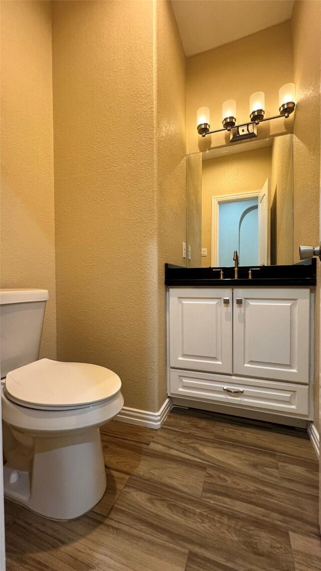 712 Lettie St, Richmond, TX 77469 - half bathroom with toilet, baseboards, vanity, wood finished floors, and a textured wall