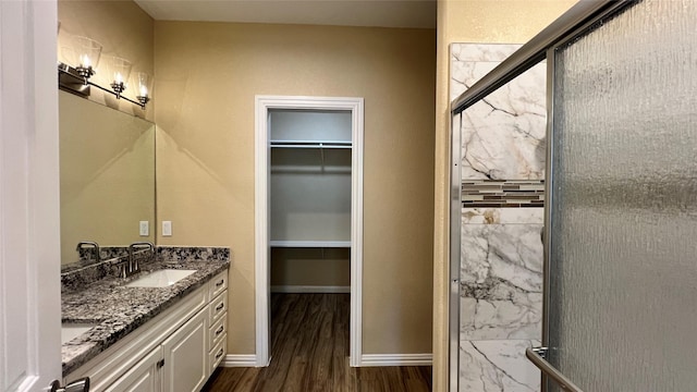 712 Lettie St, Richmond, TX 77469 - bathroom with a shower stall, wood finished floors, a spacious closet, double vanity, and baseboards