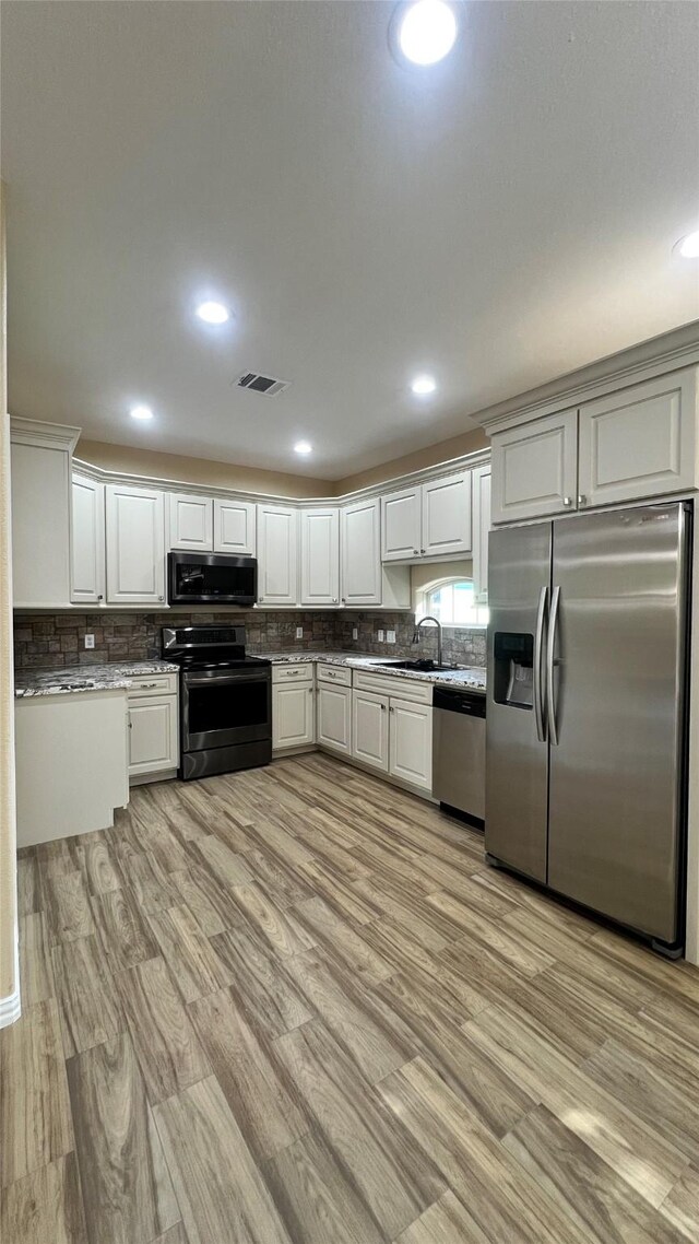 712 Lettie St, Richmond, TX 77469 - kitchen featuring appliances with stainless steel finishes, a sink, light wood-style flooring, backsplash, and recessed lighting