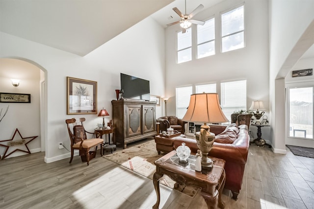 356 Selah Ct, Alvin, TX 77511 - living room featuring arched walkways, light wood finished floors, a towering ceiling, healthy amount of natural light, and a ceiling fan