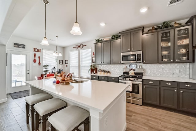 356 Selah Ct, Alvin, TX 77511 - kitchen featuring appliances with stainless steel finishes, light countertops, backsplash, a kitchen breakfast bar, and a kitchen island with sink