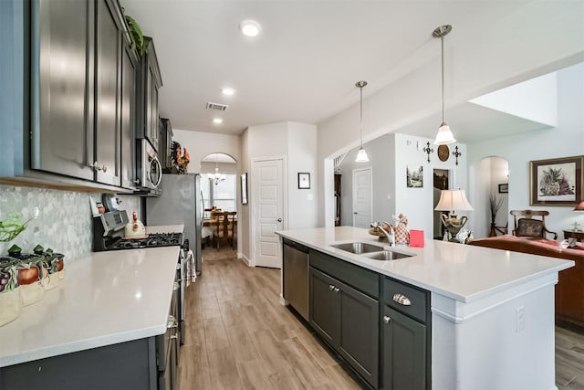 356 Selah Ct, Alvin, TX 77511 - kitchen featuring arched walkways, a sink, stainless steel appliances, tasteful backsplash, and light wood-style floors