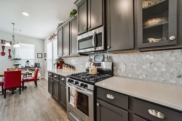 356 Selah Ct, Alvin, TX 77511 - kitchen featuring appliances with stainless steel finishes, light countertops, tasteful backsplash, hanging light fixtures, and glass insert cabinets