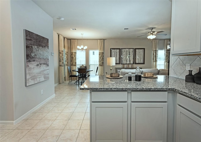 214 Emerald Thicket Ln, Humble, TX 77336 - kitchen with a peninsula, decorative backsplash, a chandelier, open floor plan, and light stone countertops