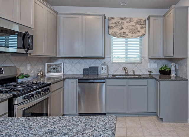 214 Emerald Thicket Ln, Humble, TX 77336 - kitchen featuring stainless steel appliances, a sink, gray cabinetry, and dark stone counters