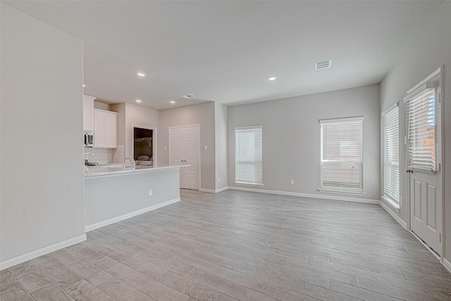 24705 Thornbluff Briar Trl, Huffman, TX 77336 - unfurnished living room featuring light wood-style floors, a sink, baseboards, and recessed lighting
