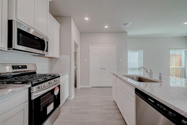 24705 Thornbluff Briar Trl, Huffman, TX 77336 - kitchen with appliances with stainless steel finishes, a sink, backsplash, light stone countertops, and white cabinetry
