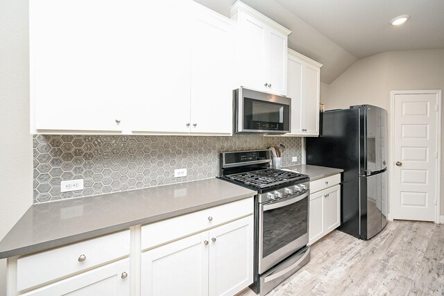 11210 Victoria Hollow Trce, Richmond, TX 77406 - kitchen featuring appliances with stainless steel finishes, light wood-type flooring, tasteful backsplash, white cabinets, and vaulted ceiling