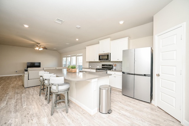 11210 Victoria Hollow Trce, Richmond, TX 77406 - kitchen with appliances with stainless steel finishes, a sink, white cabinets, an island with sink, and ceiling fan