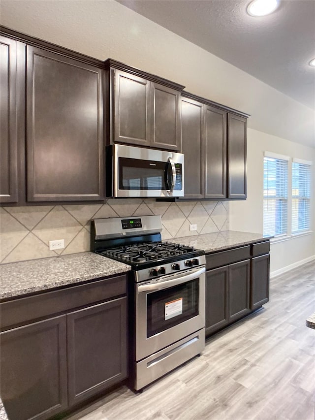 27203 Blue Pool Dr, Katy, TX 77493 - kitchen with stainless steel appliances, backsplash, dark brown cabinets, light wood-style flooring, and baseboards