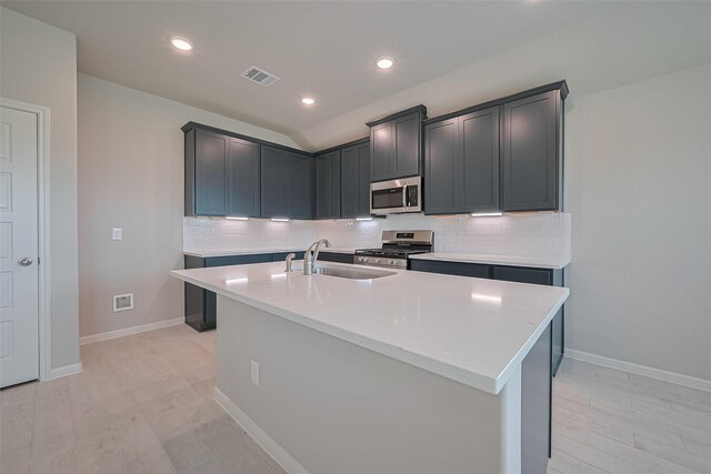 27203 Blue Pool Dr, Katy, TX 77493 - kitchen featuring appliances with stainless steel finishes, a sink, decorative backsplash, light countertops, and a center island with sink