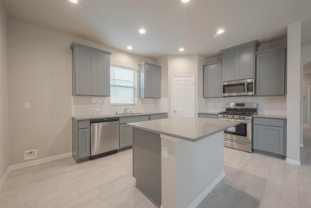 1464 Sundown Glen Ln, Katy, TX 77493 - kitchen with appliances with stainless steel finishes, gray cabinets, light wood-type flooring, a sink, and backsplash