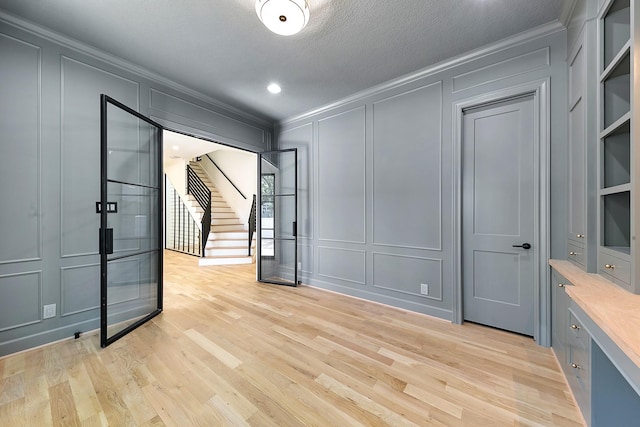 4528 S Evergreen St, Bellaire, TX 77401 - spare room with a decorative wall, crown molding, light wood-style flooring, recessed lighting, and french doors