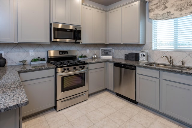 1472 Sundown Gln, Katy, TX 77493 - kitchen featuring appliances with stainless steel finishes, gray cabinetry, a sink, backsplash, and dark stone countertops