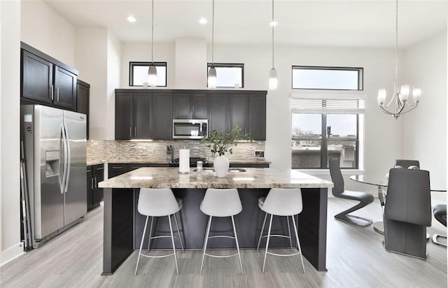 4104 Marina St, Houston, TX 77007 - kitchen with appliances with stainless steel finishes, light wood finished floors, light stone countertops, an island with sink, and recessed lighting