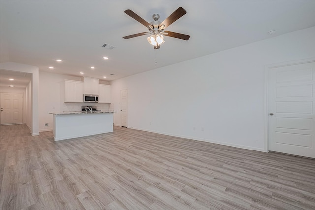 17807 Cappadocia Trl, Tomball, TX 77377 - unfurnished living room with a ceiling fan, light wood-style flooring, and recessed lighting
