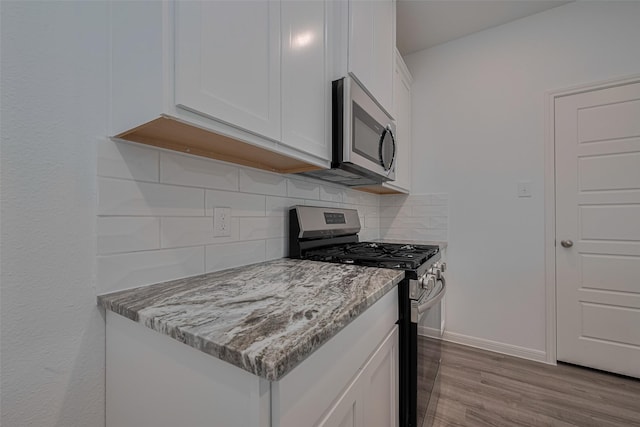 17807 Cappadocia Trl, Tomball, TX 77377 - kitchen with stainless steel appliances, white cabinetry, dark wood-style floors, decorative backsplash, and light stone countertops
