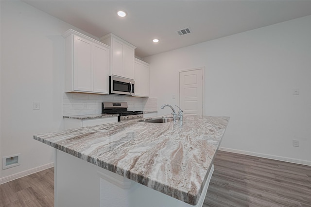 17807 Cappadocia Trl, Tomball, TX 77377 - kitchen featuring appliances with stainless steel finishes, wood finished floors, white cabinets, a center island with sink, and recessed lighting