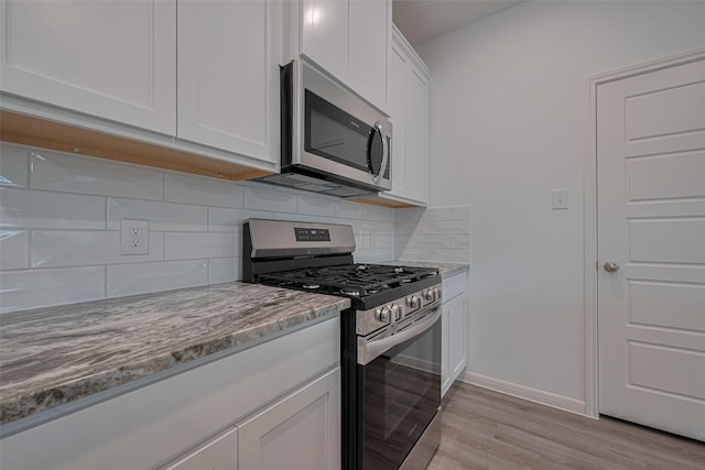 17807 Cappadocia Trl, Tomball, TX 77377 - kitchen with appliances with stainless steel finishes, light wood-style floors, white cabinetry, light stone counters, and backsplash