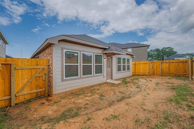 17807 Cappadocia Trl, Tomball, TX 77377 - rear view of house with a fenced backyard, a gate, brick siding, and roof with shingles