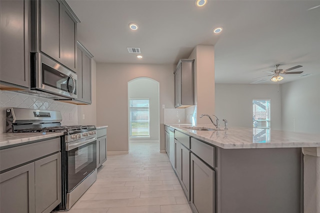 22807 Ephesus Ave, Tomball, TX 77377 - kitchen with stainless steel appliances, gray cabinets, arched walkways, a sink, and recessed lighting