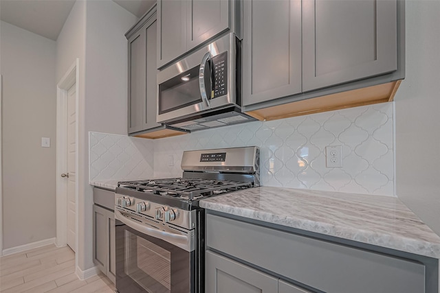 22807 Ephesus Ave, Tomball, TX 77377 - kitchen with appliances with stainless steel finishes, gray cabinetry, tasteful backsplash, baseboards, and light wood-type flooring