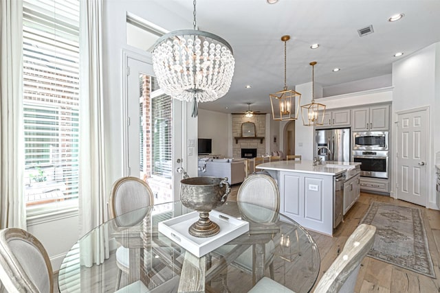 10311 Belvamera Rd, Richmond, TX 77407 - dining space featuring a chandelier, light wood finished floors, recessed lighting, and a stone fireplace