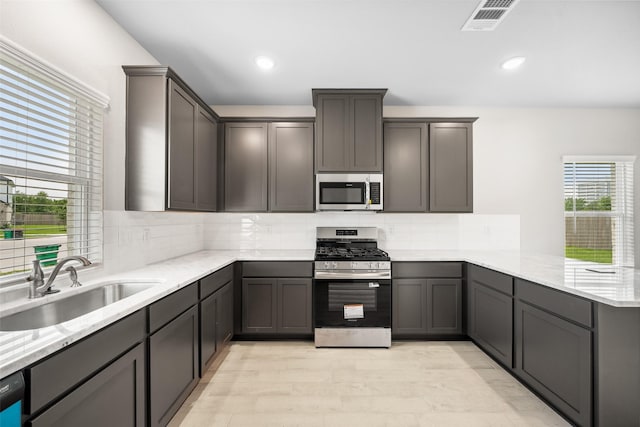 3211 Falling Brook Dr, Baytown, TX 77521 - kitchen featuring appliances with stainless steel finishes, a sink, a peninsula, tasteful backsplash, and light stone counters