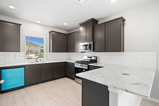 3211 Falling Brook Dr, Baytown, TX 77521 - kitchen featuring stainless steel appliances, a sink, a peninsula, decorative backsplash, and light stone counters