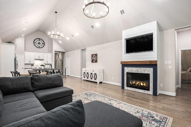3423 Crescent Vista Dr, Fulshear, TX 77441 - living area featuring a chandelier, high vaulted ceiling, light wood-style flooring, a fireplace, and baseboards