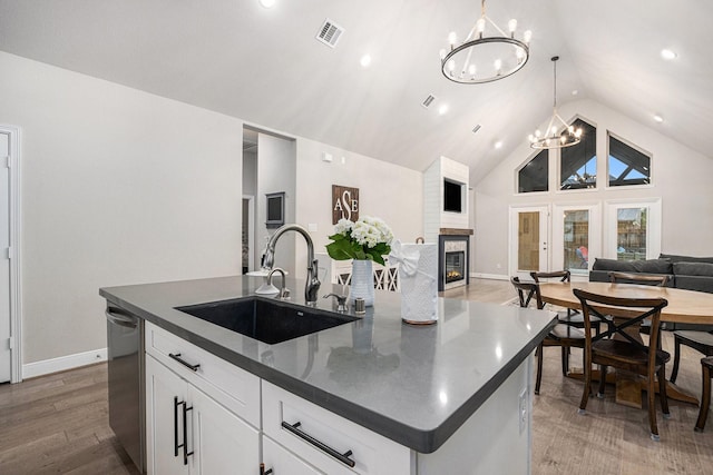 3423 Crescent Vista Dr, Fulshear, TX 77441 - kitchen featuring a sink, open floor plan, a chandelier, dark countertops, and a glass covered fireplace