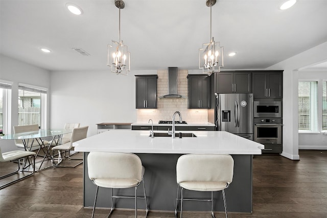 2334 Calm Channel Ct, Missouri City, TX 77459 - kitchen with appliances with stainless steel finishes, a chandelier, wall chimney range hood, a center island with sink, and recessed lighting