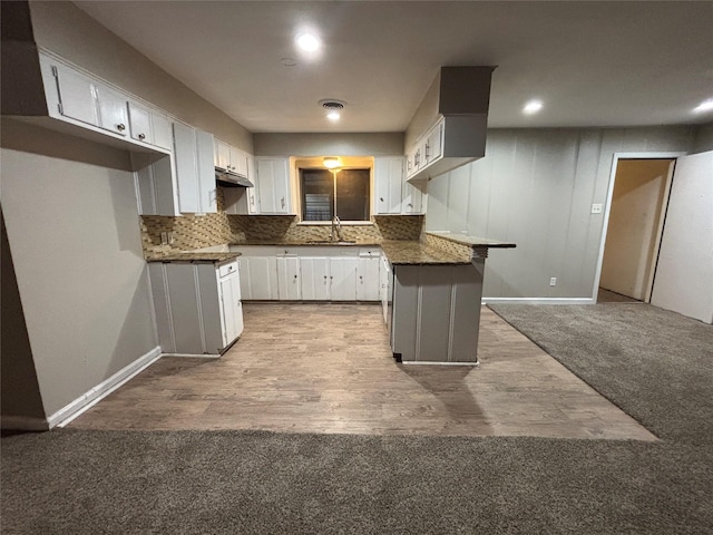 1102 Laurentide St, Houston, TX 77029 - kitchen featuring a sink, under cabinet range hood, a peninsula, carpet floors, and tasteful backsplash