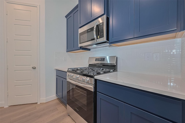 8933 Grovner Pl, Houston, TX 77055 - kitchen featuring appliances with stainless steel finishes, blue cabinetry, backsplash, light wood finished floors, and light stone counters
