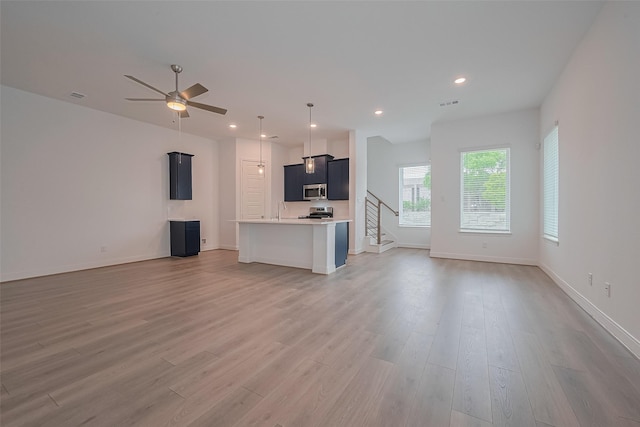 8933 Grovner Pl, Houston, TX 77055 - unfurnished living room featuring light wood-style floors, ceiling fan, recessed lighting, stairs, and baseboards