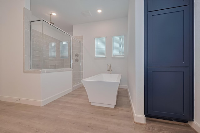 8933 Grovner Pl, Houston, TX 77055 - bathroom with a tile shower, a freestanding tub, wood finished floors, baseboards, and recessed lighting