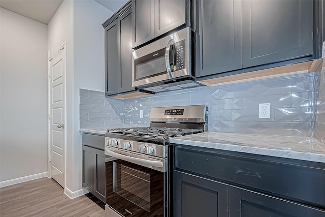 10155 Red Snapper Rd, Magnolia, TX 77354 - kitchen with appliances with stainless steel finishes, light wood-style flooring, baseboards, light stone countertops, and tasteful backsplash