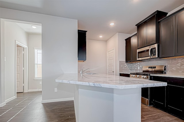 10155 Red Snapper Rd, Magnolia, TX 77354 - kitchen with stainless steel appliances, dark brown cabinets, decorative backsplash, light stone countertops, and a sink