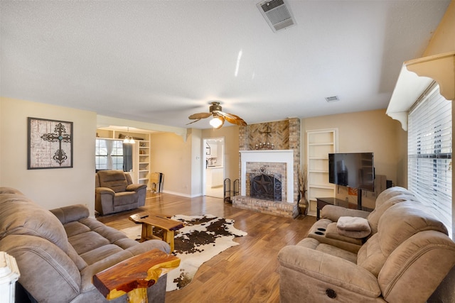 90 Fishermans Bend Dr, Point Blank, TX 77364 - living area with built in features, a ceiling fan, wood finished floors, a fireplace, and a textured ceiling