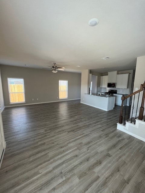 27290 Axis Deer Trl, Magnolia, TX 77354 - unfurnished living room featuring baseboards, dark wood finished floors, a ceiling fan, and stairs