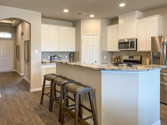 2220 Manila Ln, Texas City, TX 77568 - kitchen featuring appliances with stainless steel finishes, arched walkways, dark wood finished floors, tasteful backsplash, and recessed lighting