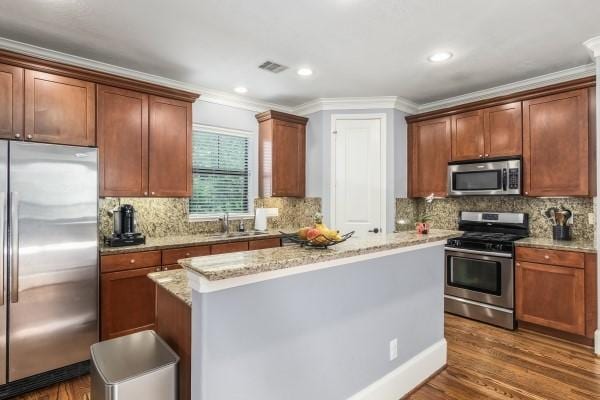 1042 W 23rd St Unit D, Houston, TX 77008 - kitchen with appliances with stainless steel finishes, a sink, a kitchen island, crown molding, and light stone countertops