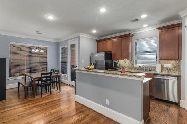 1042 W 23rd St Unit D, Houston, TX 77008 - kitchen featuring appliances with stainless steel finishes, a sink, crown molding, a chandelier, and decorative backsplash
