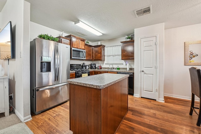 850 Driftwood Ln, La Marque, TX 77568 - kitchen with black appliances, a kitchen island, baseboards, a textured ceiling, and light wood finished floors
