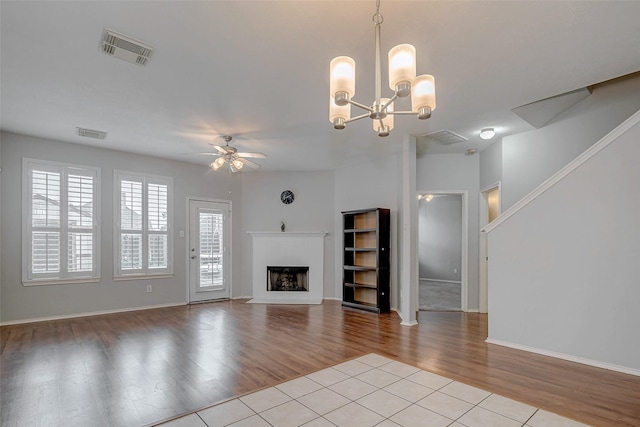 2710 Marigny Dr, Houston, TX 77014 - unfurnished living room featuring a ceiling fan, wood finished floors, a fireplace, a chandelier, and baseboards