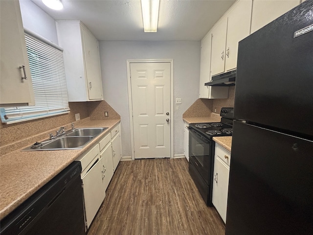 6210 Annunciation St, Houston, TX 77016 - kitchen with black appliances, under cabinet range hood, dark wood-type flooring, white cabinetry, and light countertops